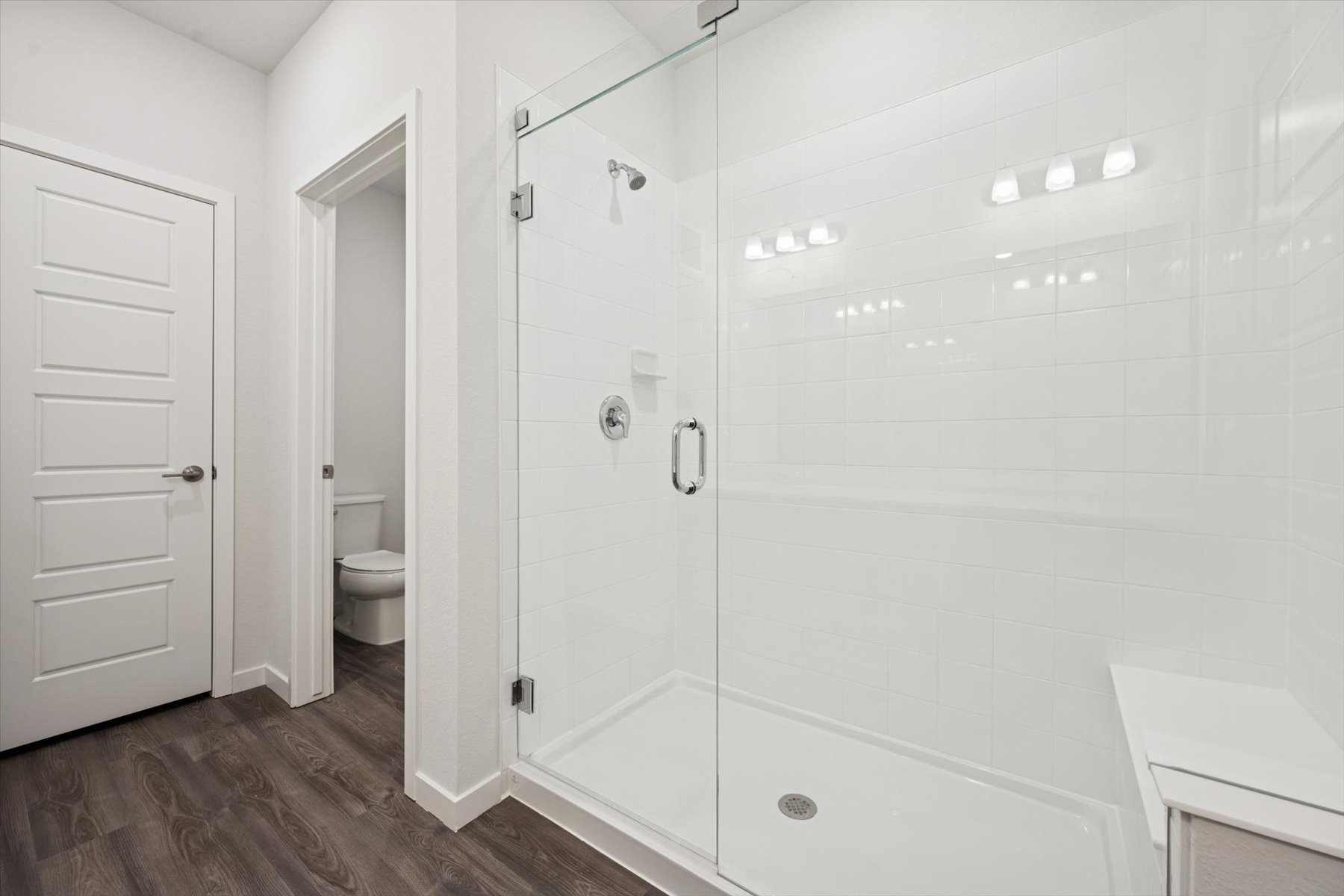 A bathroom with a shower unit and toilet.