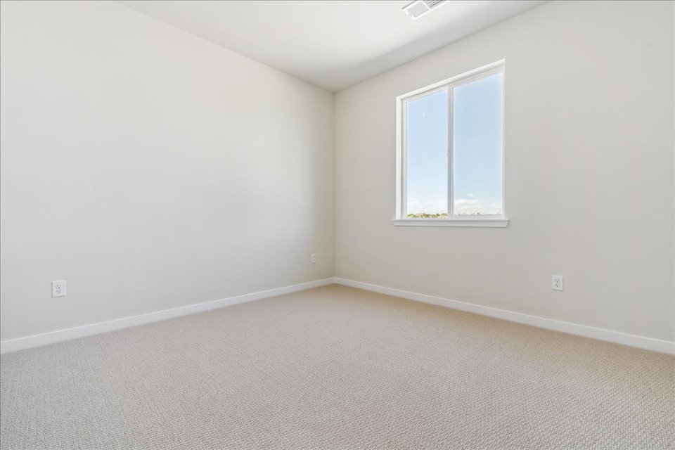A room with a window and a white wall.