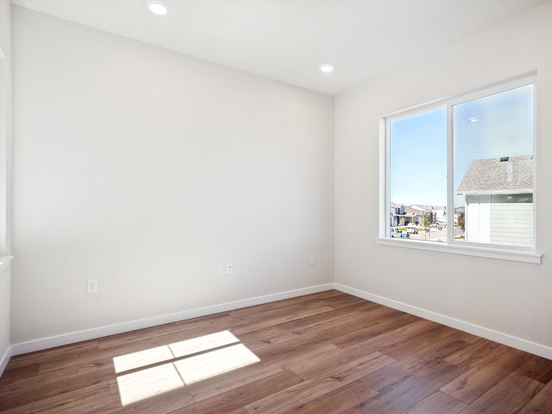 A room with a wood floor and a window with a wood floor.