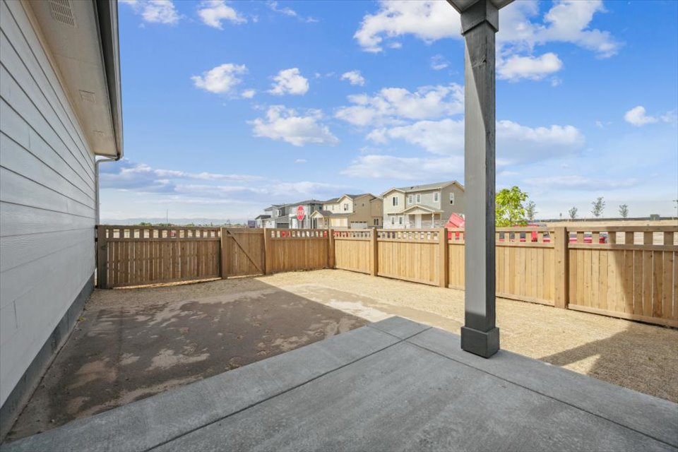 A fenced off area with a wood railing and buildings in the background.