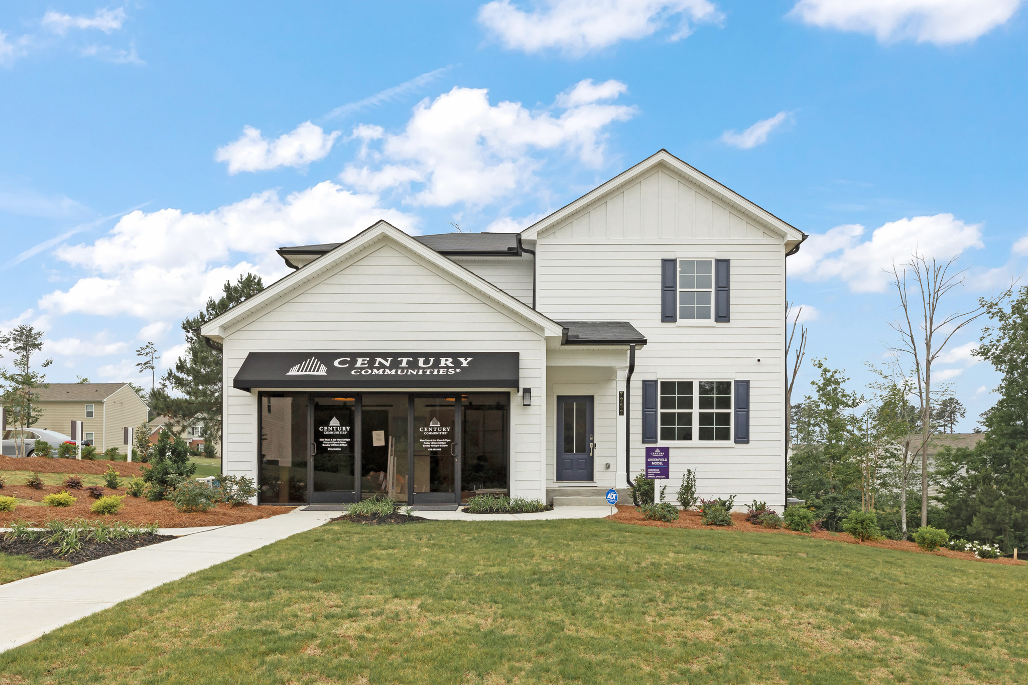 A white building with a sign on it with Southfork Ranch in the background.