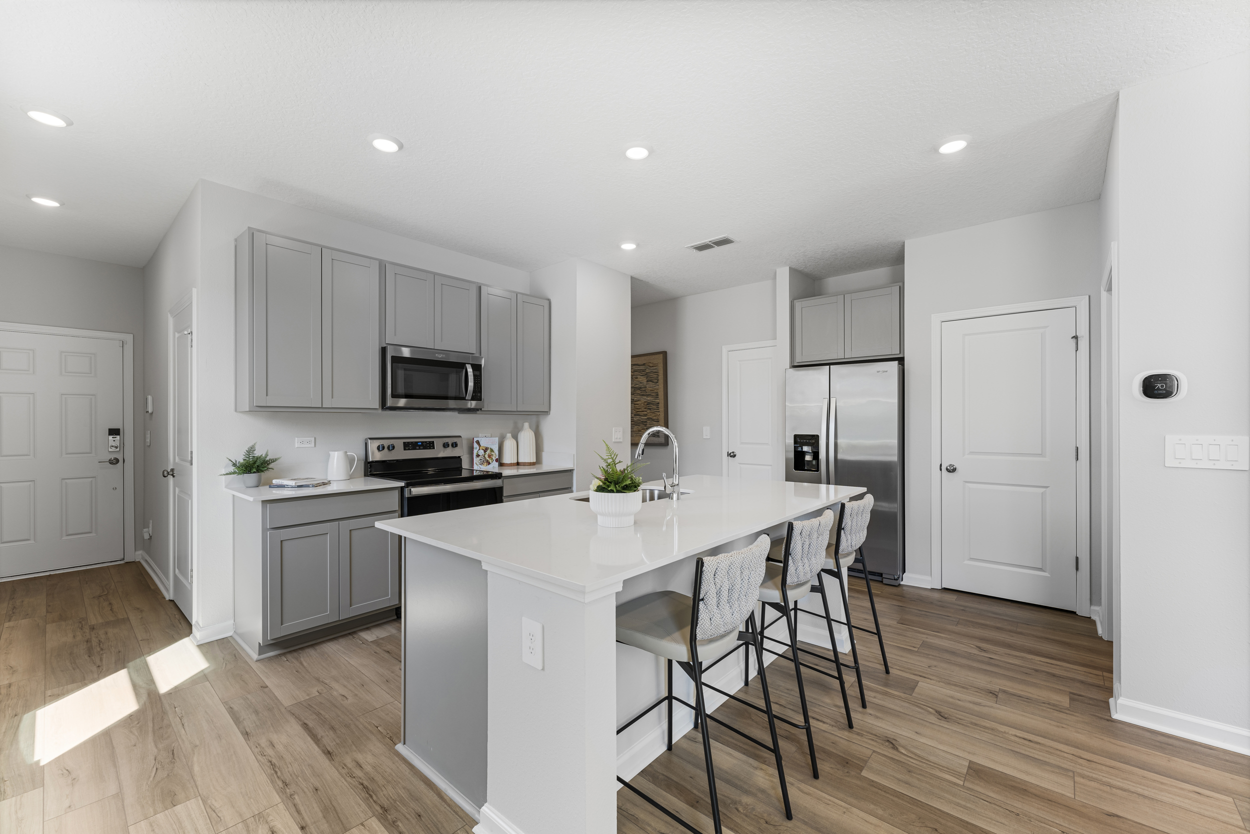 Sanibel Model Home Kitchen with White Counters and Stainless Steel Appliances at The Landings at Pecan Park in Jacksonville