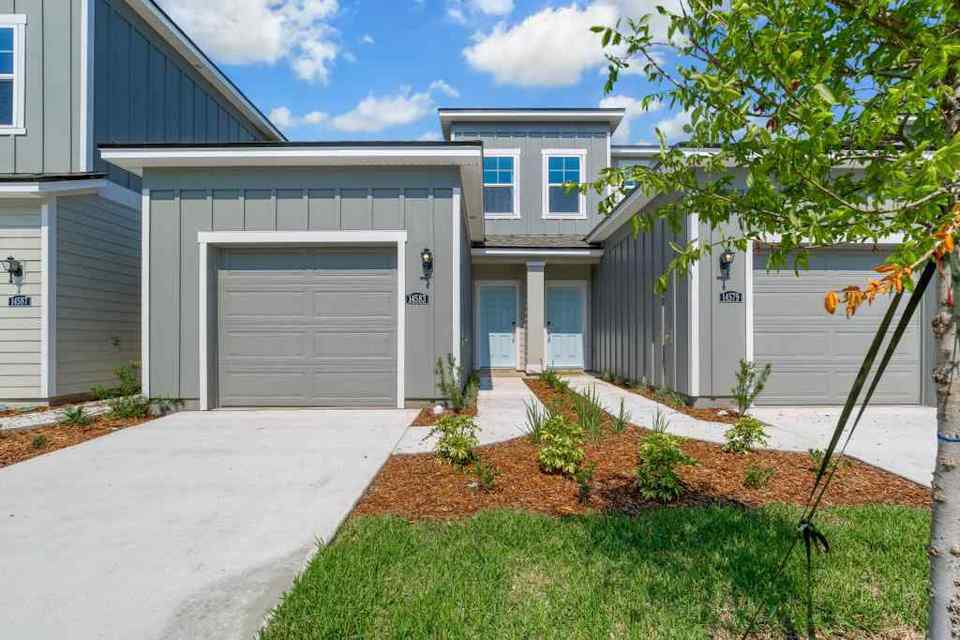 A house with garages and a tree in the front.