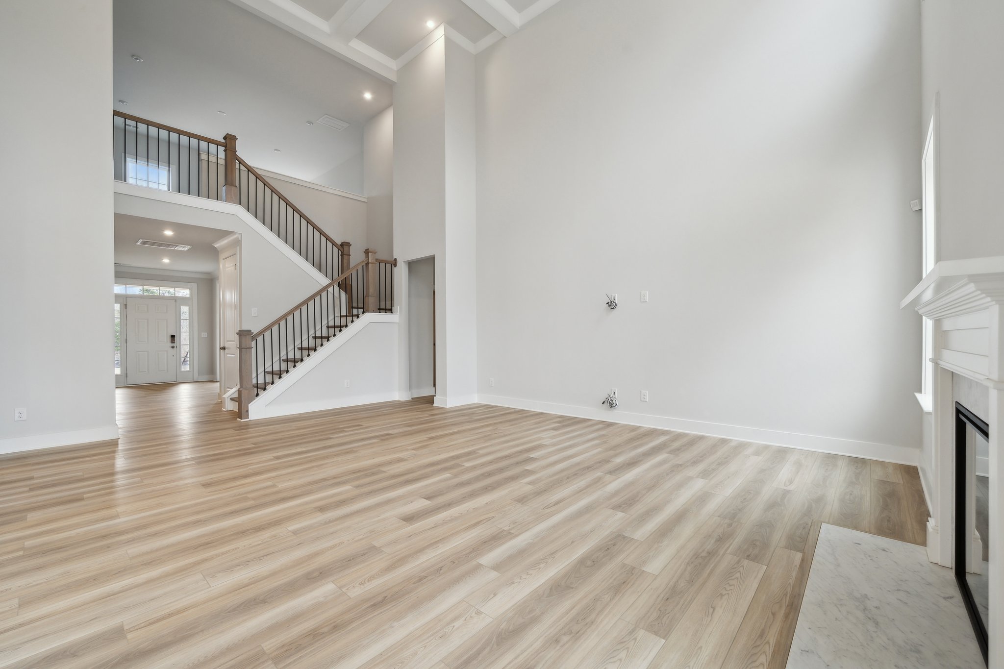 A large empty room with a wood floor and a staircase.