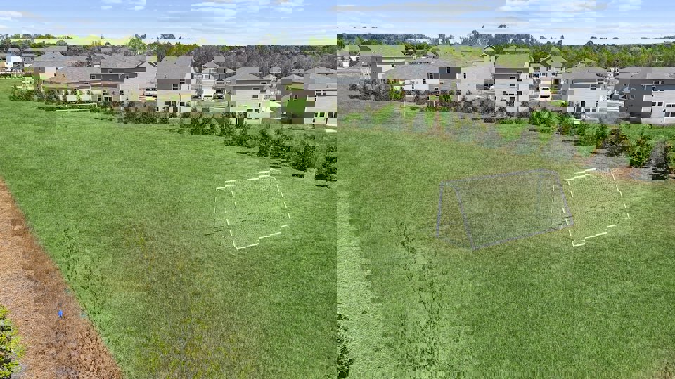 A football field with houses in the background.