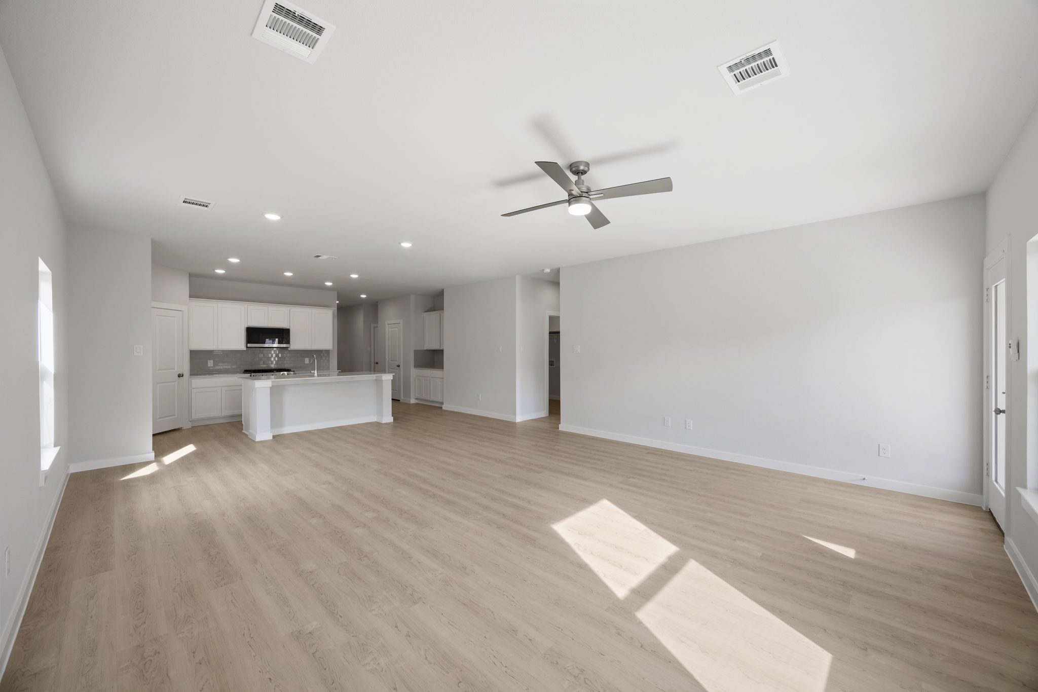 A large empty room with a wood floor and a ceiling fan.