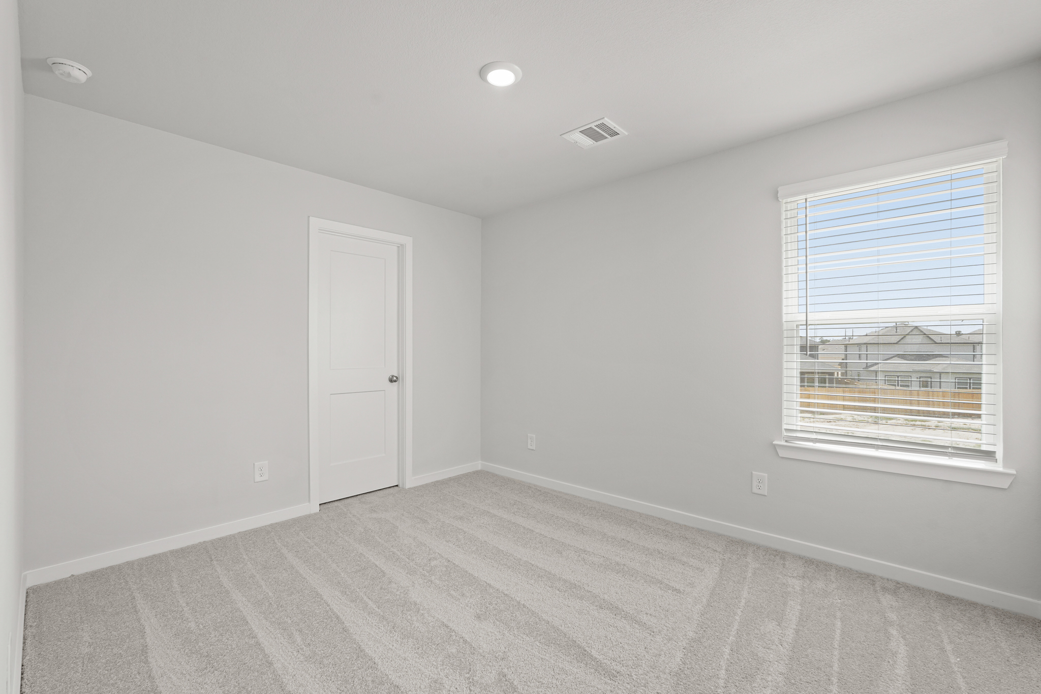 A room with a white door and a white wall with a window.