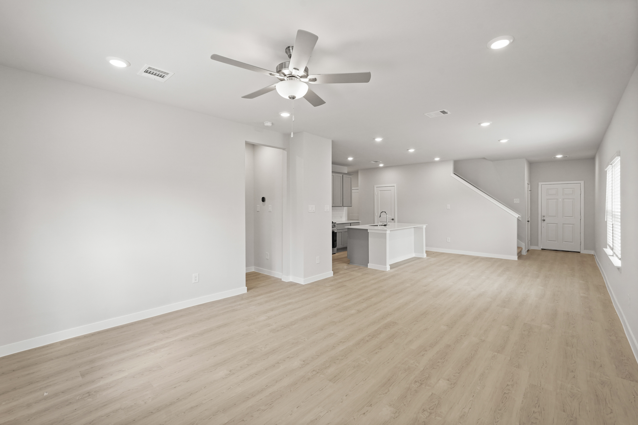 A large empty room with a ceiling fan and a wood floor.
