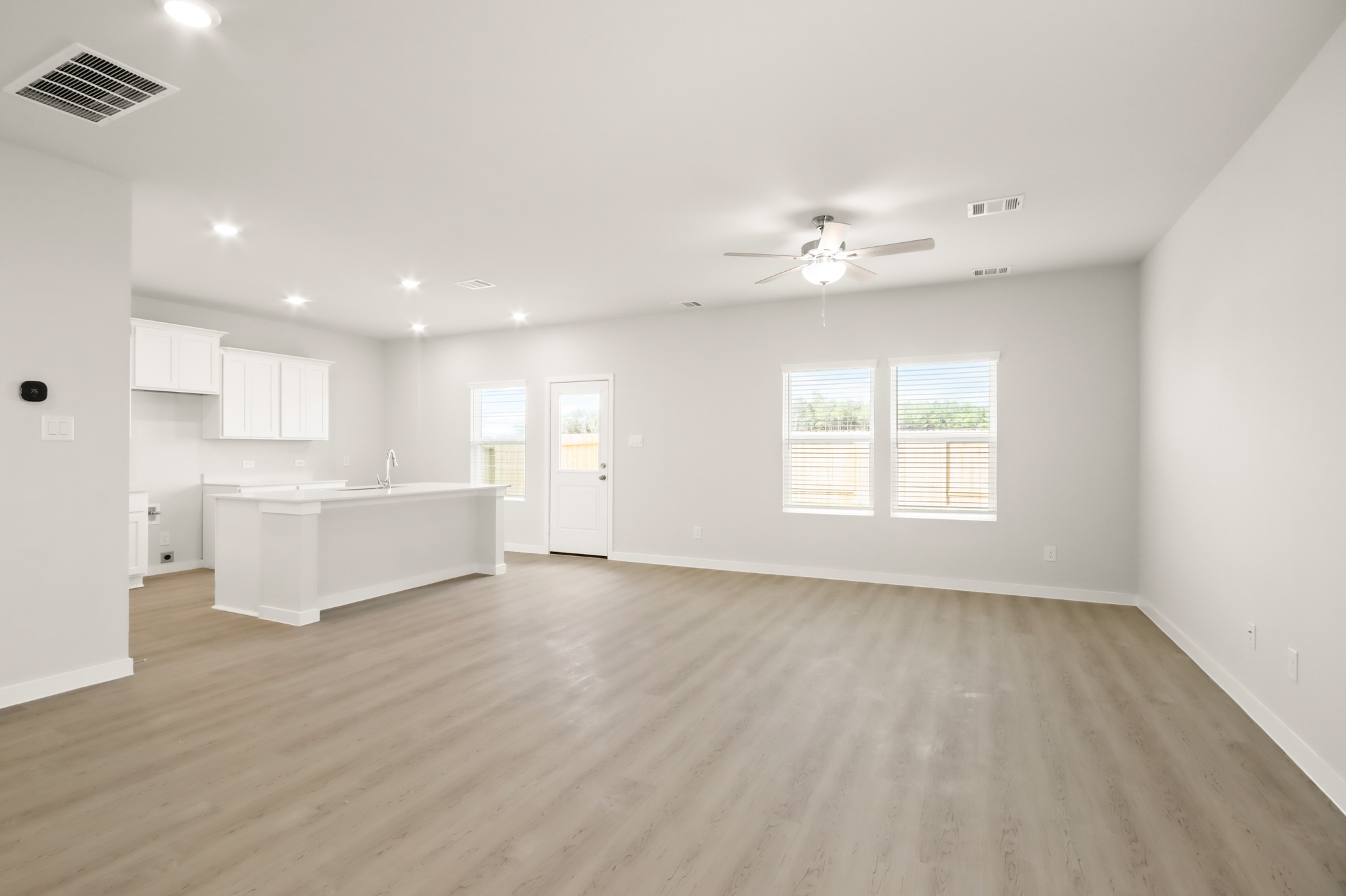 A large empty room with a white countertop and a ceiling fan.