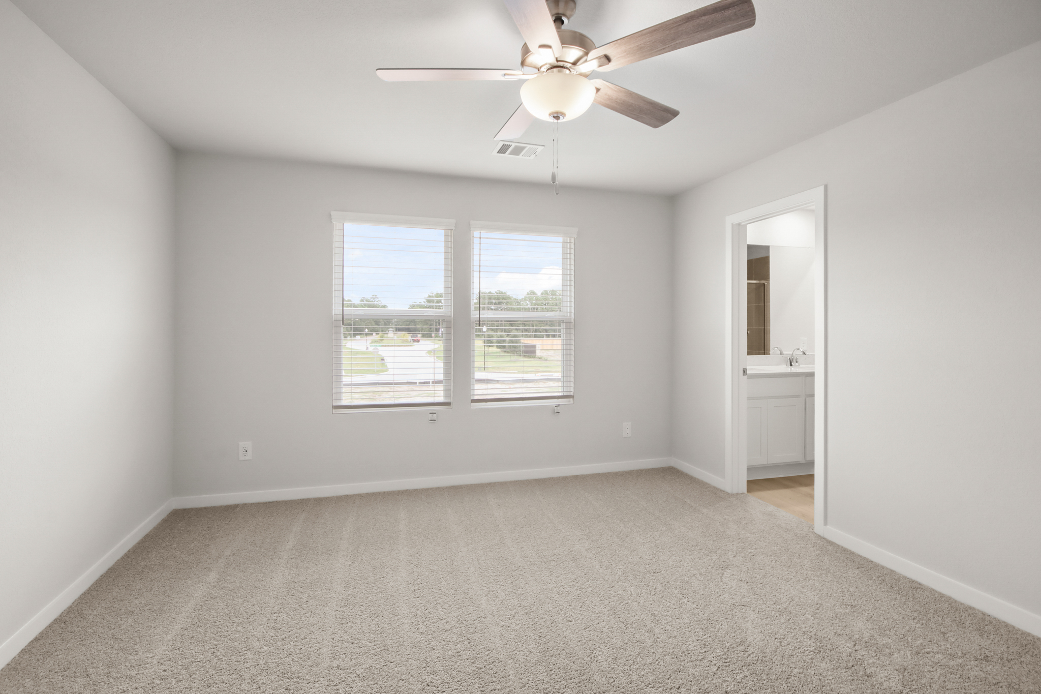 A large white room with a ceiling fan and a window.