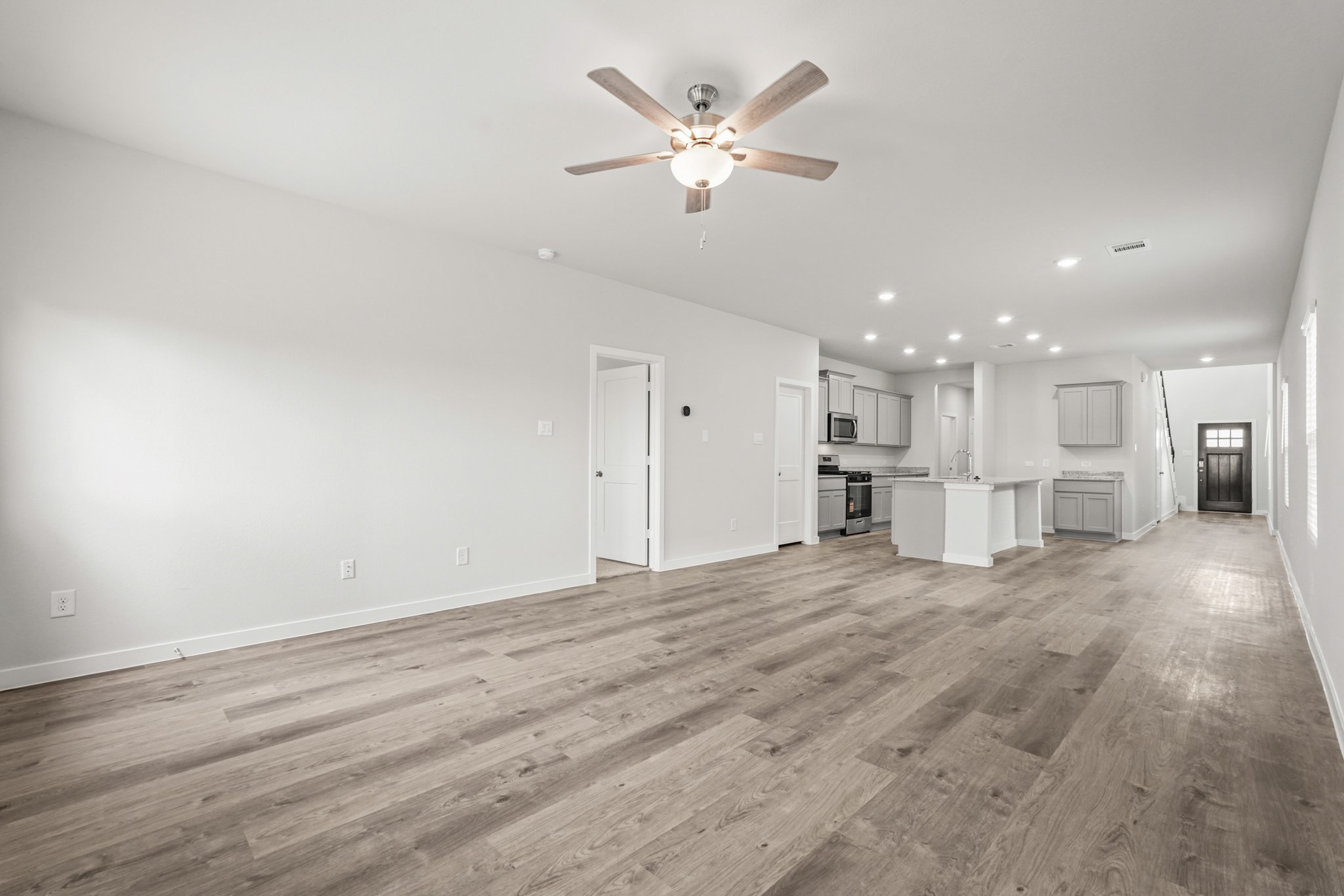 A large empty room with a ceiling fan and wood floors.