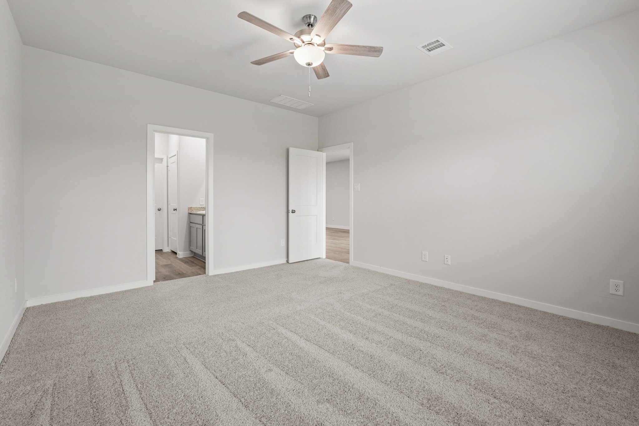 A room with a ceiling fan and a carpet.