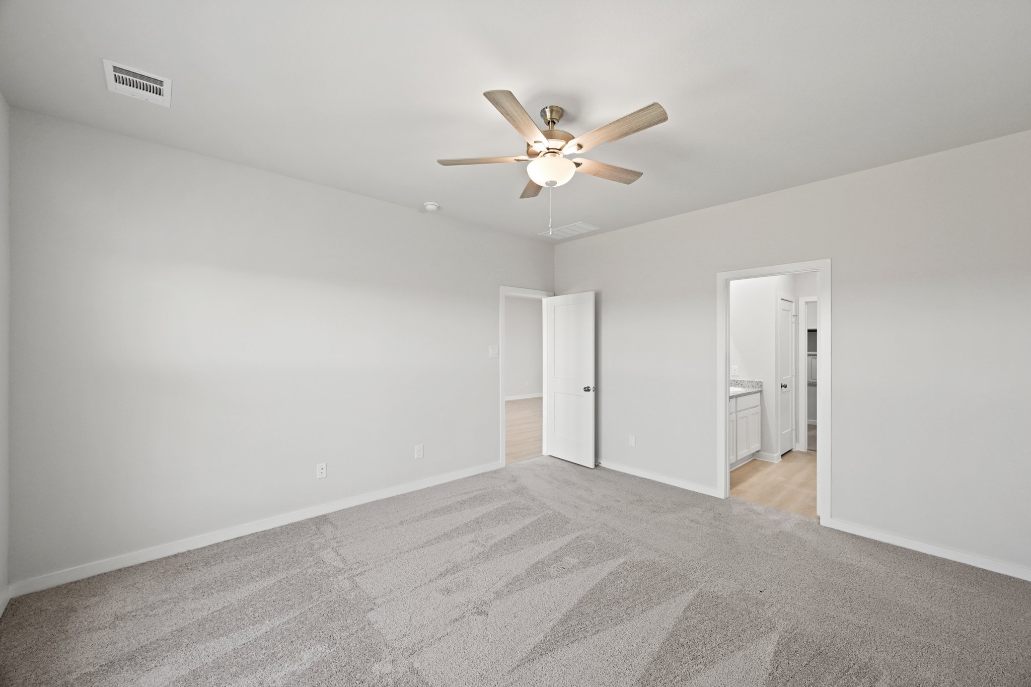 A room with a ceiling fan and a carpet.