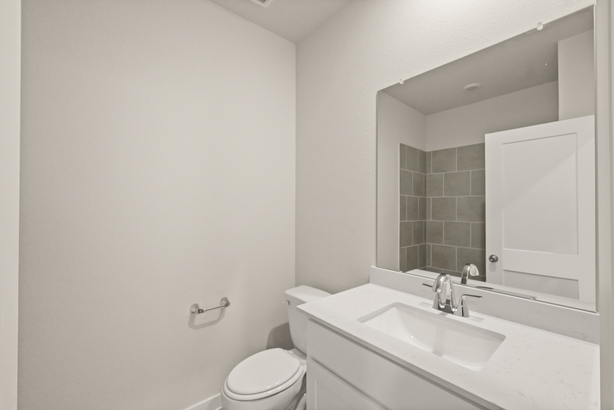 A bathroom with a sink toilet and mirror.