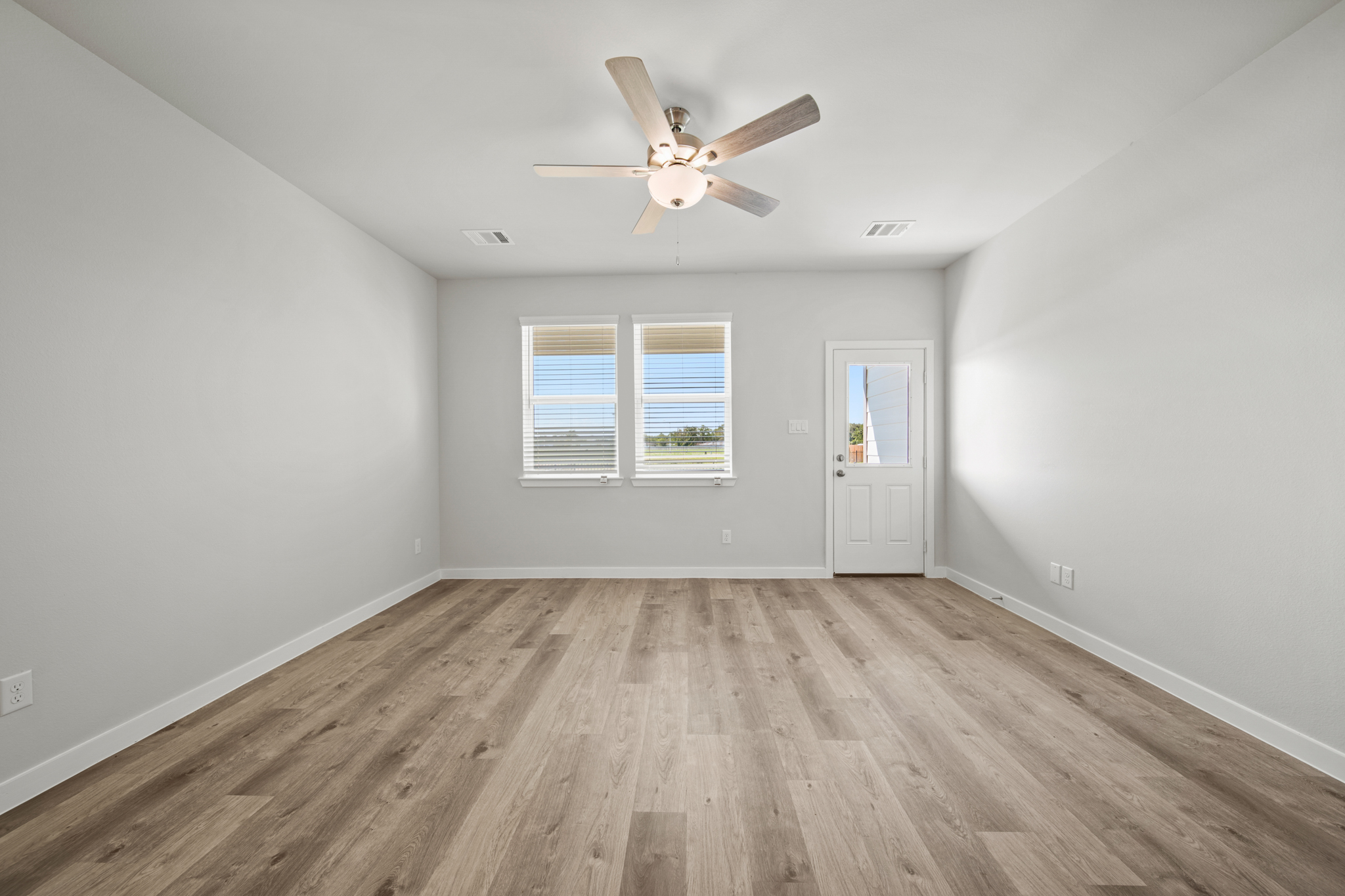 A room with a ceiling fan and a wood floor.