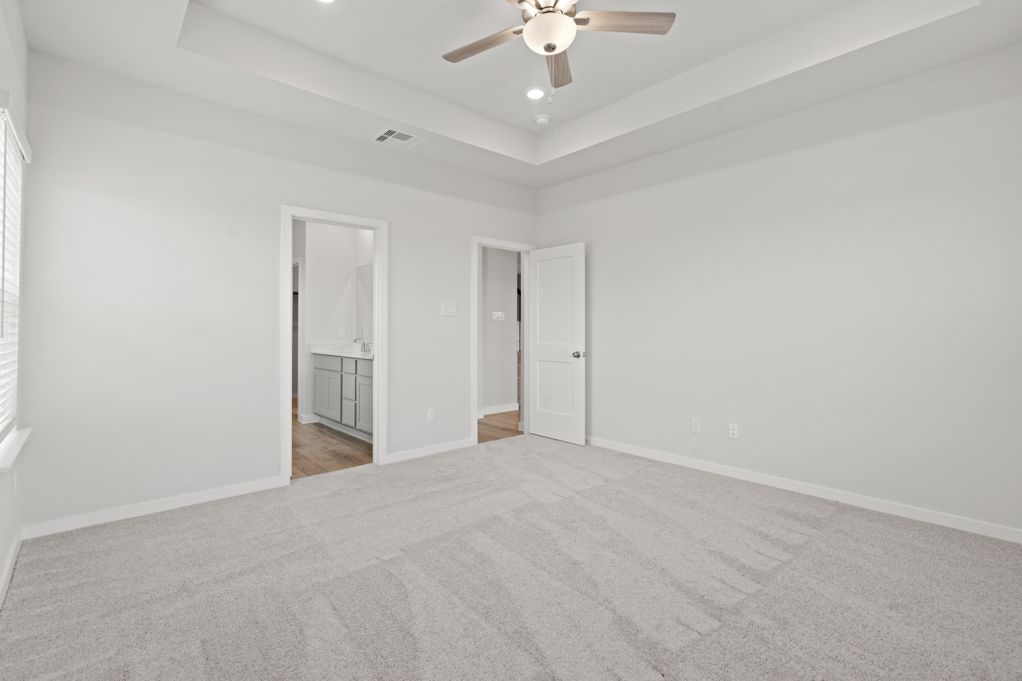 A room with a ceiling fan and a carpet.