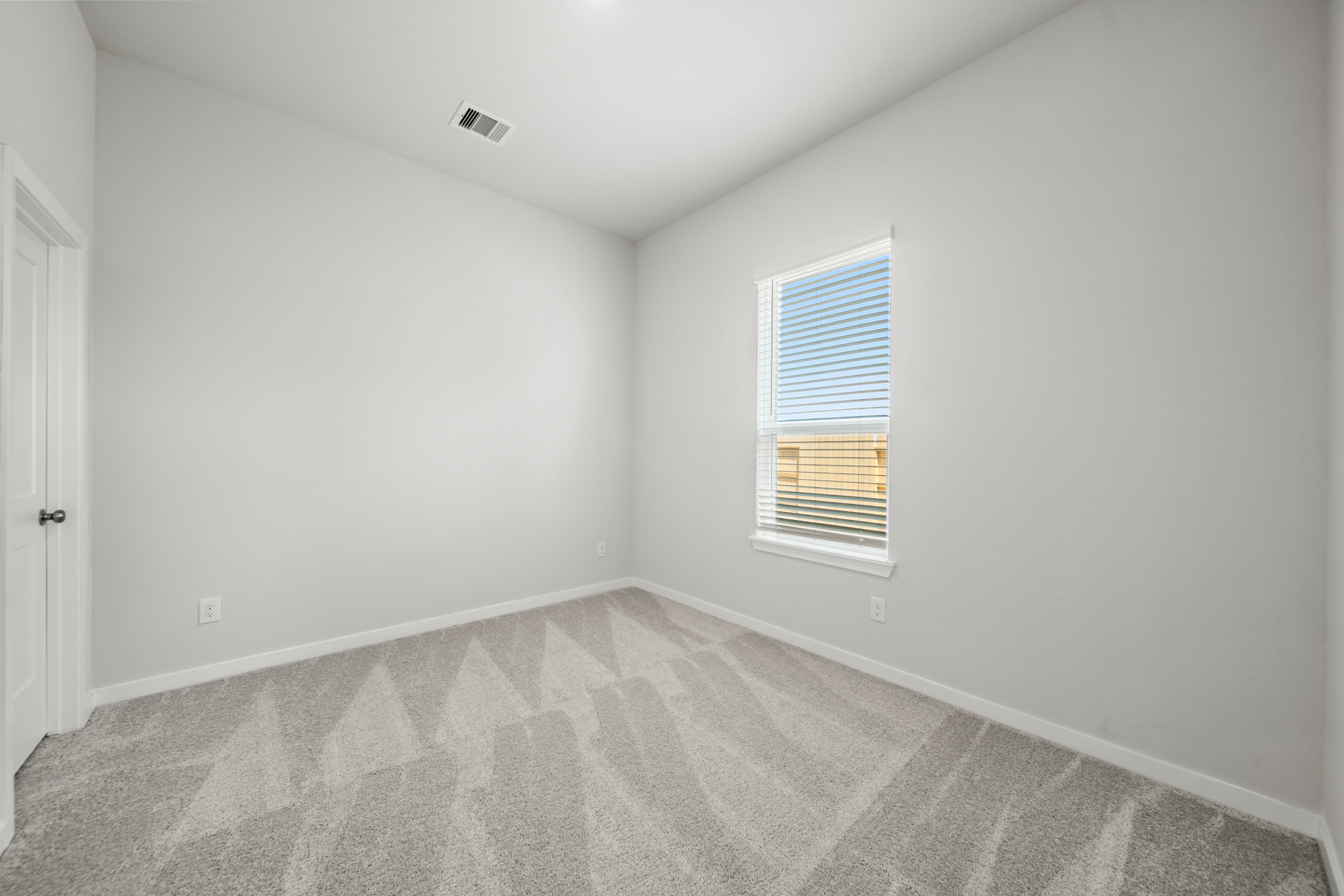 A room with a carpet and a window.