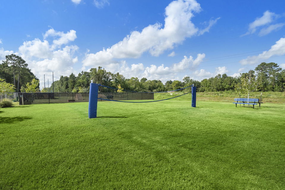 A grassy area with a fence and a playground in the background.