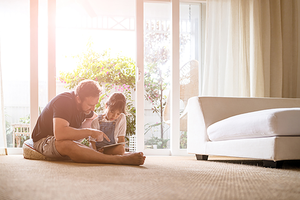 A person and a child sitting on the floor reading a book.