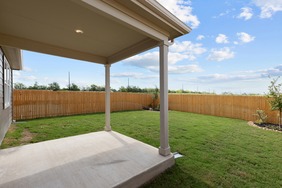 A covered patio with a fence and a wood fence.