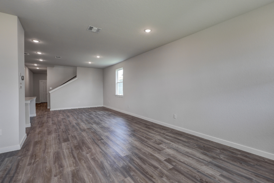 A room with a wood floor and a white wall with a window.