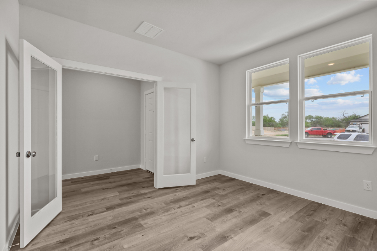 A room with a wood floor and a window with a view of the ocean.