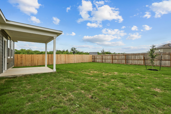 A fenced in yard with a house and a tree.