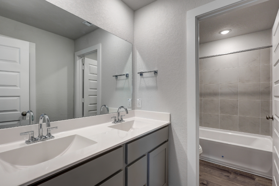A bathroom with a tub sink and a mirror.