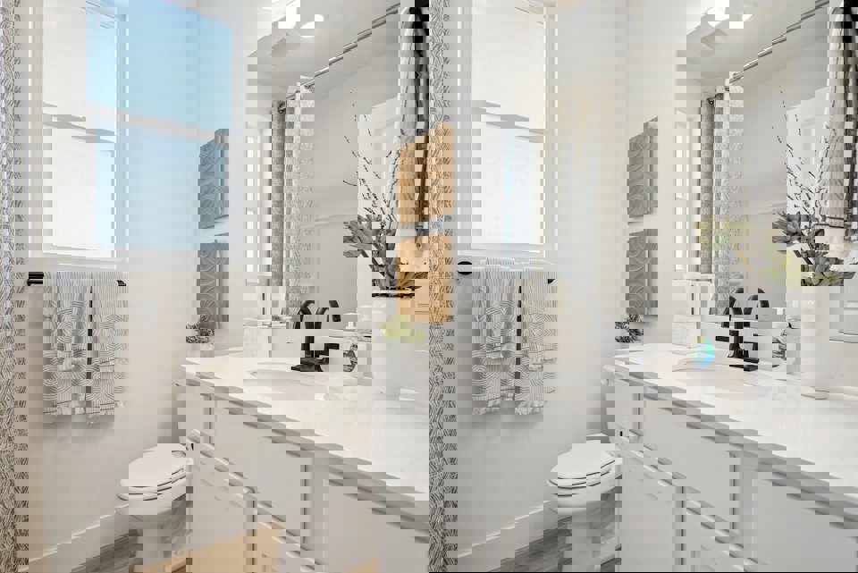 A bathroom with a sink toilet and mirror.