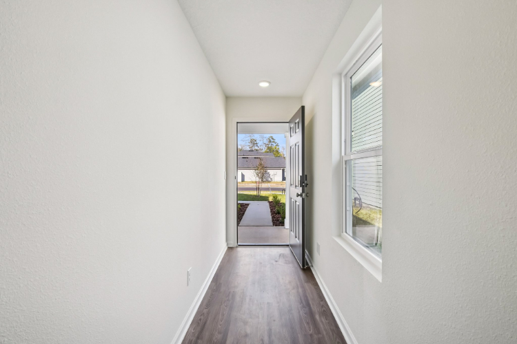 A hallway with windows and a wood floor.